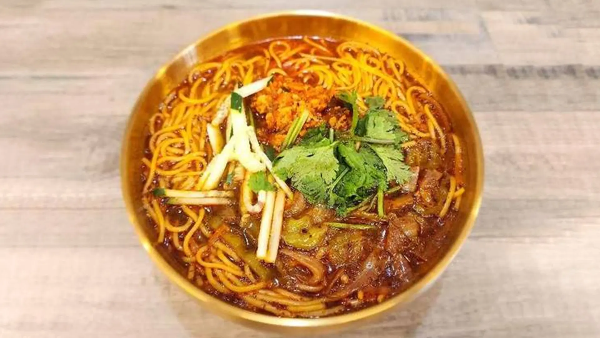 Noodles in a spicy broth garnished with cilantro and other seasonings at Mala Mini Restaurant in Palisades Park.
